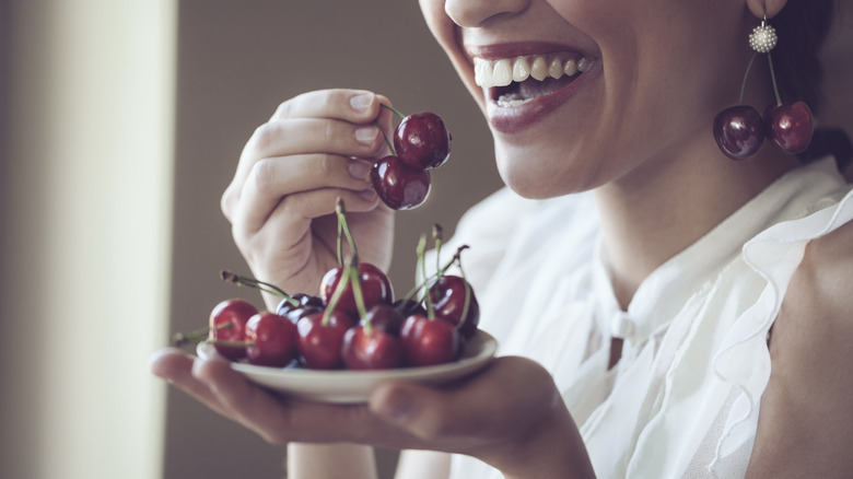 woman eating cherries from plate