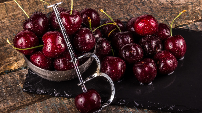 red cherries with cherry pitting tool