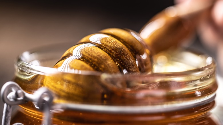 a jar of honey with a honey dipper