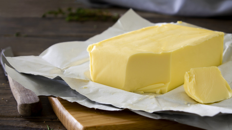 an unwrapped block of butter on a cutting board