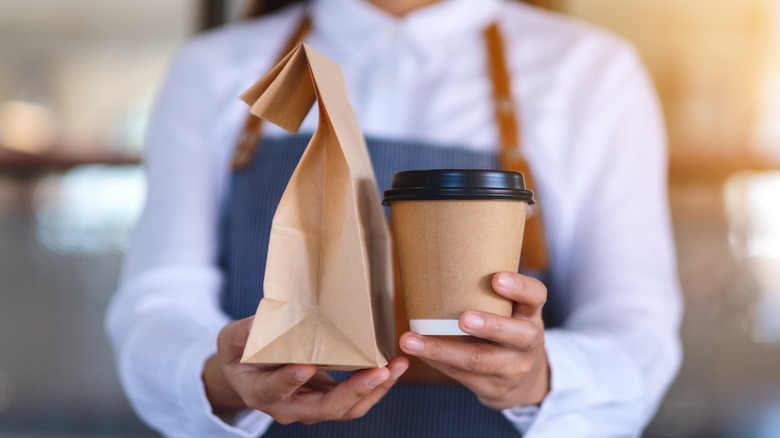 waitress holding sack and coffee