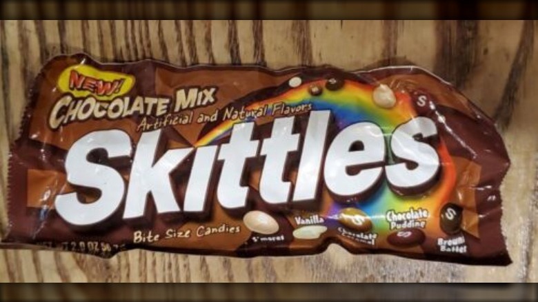 a package of skittles chocolate mix on a brown background