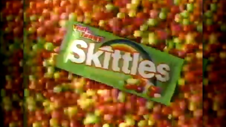 a box of tart n tangy skittles lying on a pile of skittles