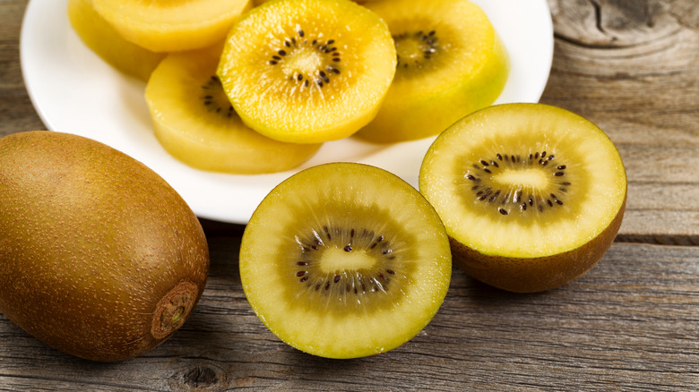 cut golden kiwis on plate and wooden table