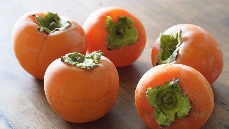 5 persimmons on wooden table