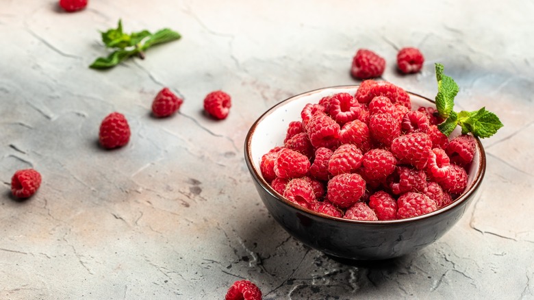 raspberries in bowl with some scattered