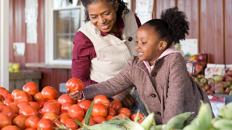 Mom and small girl shopping for tomatoes