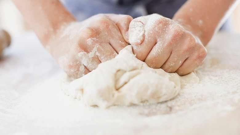 Two hands kneading dough