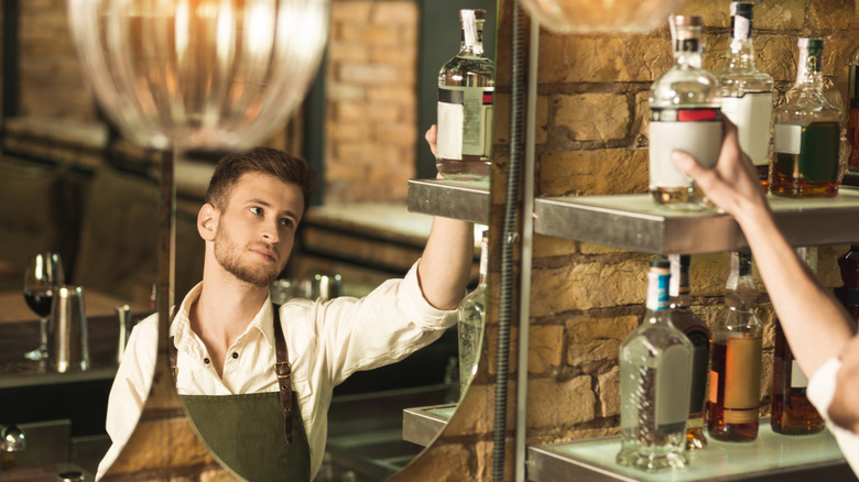 bartender reaching for top-shelf liquor