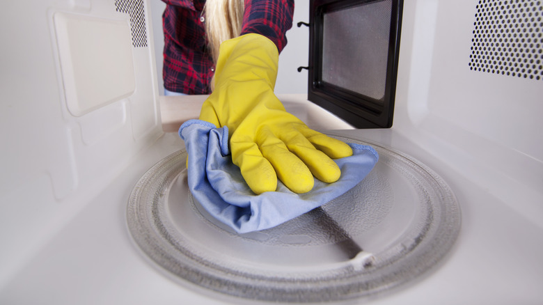 person cleaning microwave turntable