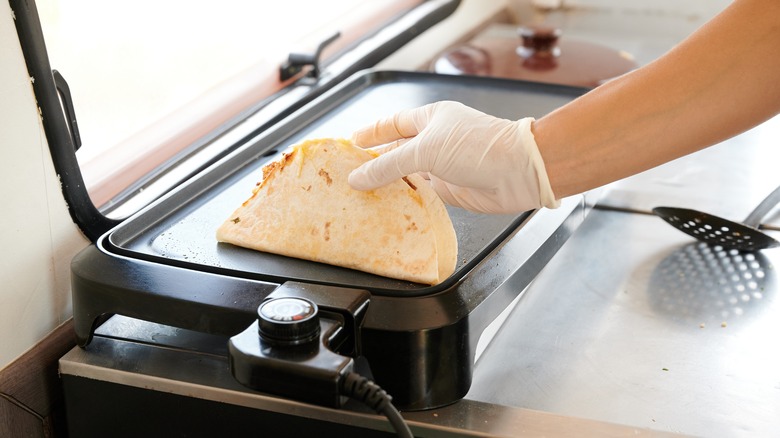 Person cooking quesadilla on electric griddle