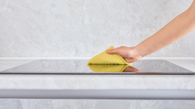 person cleaning induction cooktop