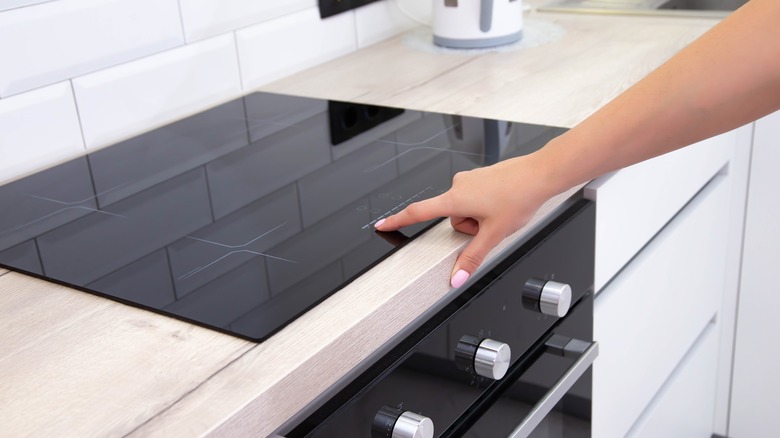 Person pressing button on induction cooktop