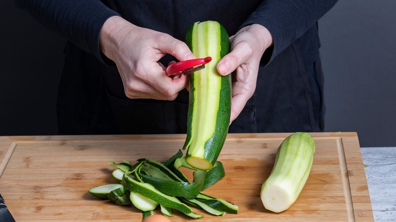 hands peeling zucchini skin