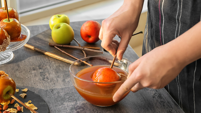 Person dipping apple in caramel