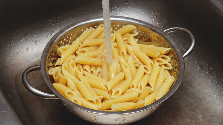 Cooked pasta in colander with water