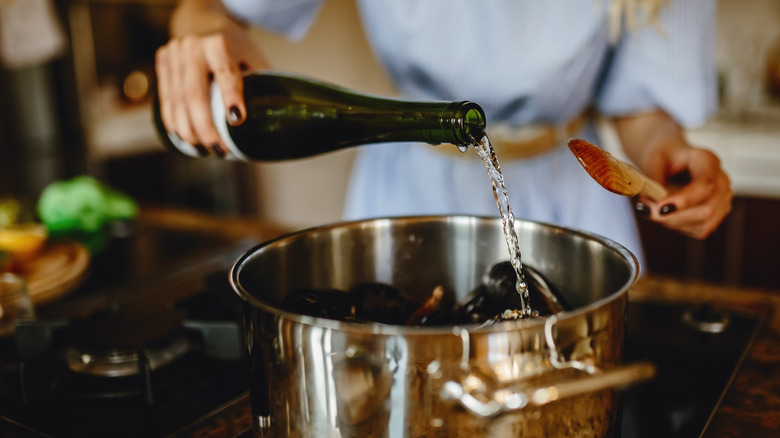 woman pouring wine into cooking pot