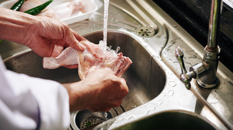 person rinsing raw meat
