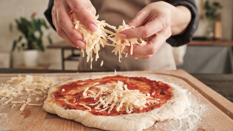 adding cheese to homemade pizza