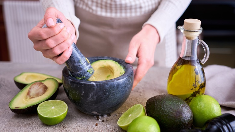 cook mashing avocado with mortar and pestle