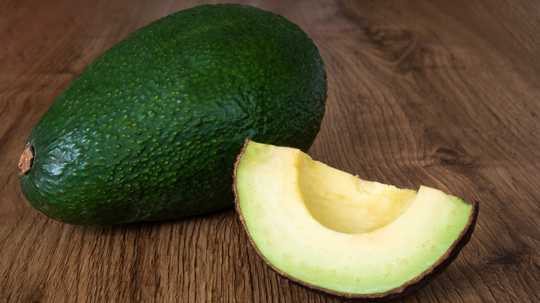 Whole and sliced unripe avocados