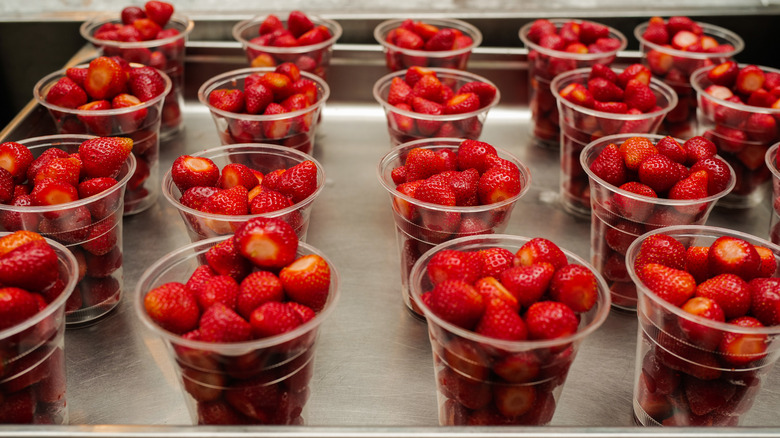 many plastic cups of strawberries