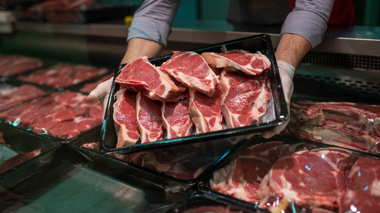 Butcher holding tray of meat