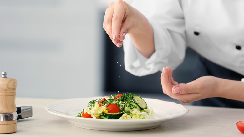 Chef adding salt to dish