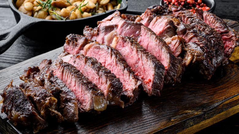 steak, wood cutting board, white beans, cast iron skillet