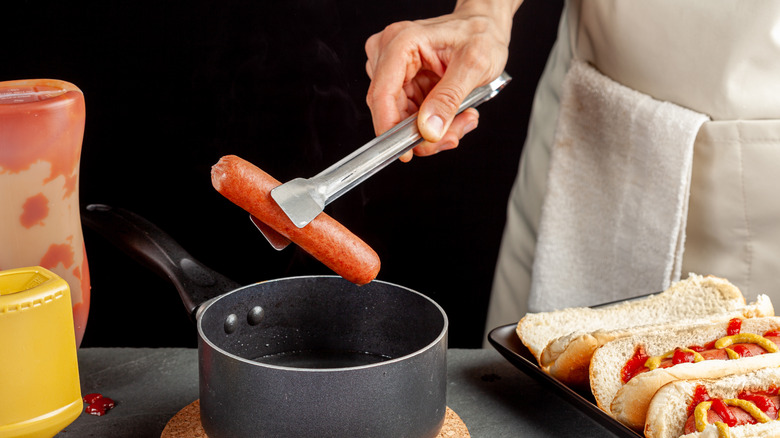 Boiled hot dog in tongs