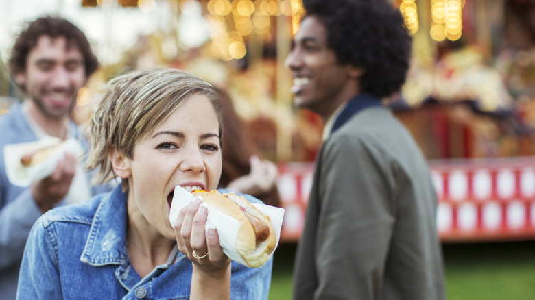 Woman eating hot dog with friends
