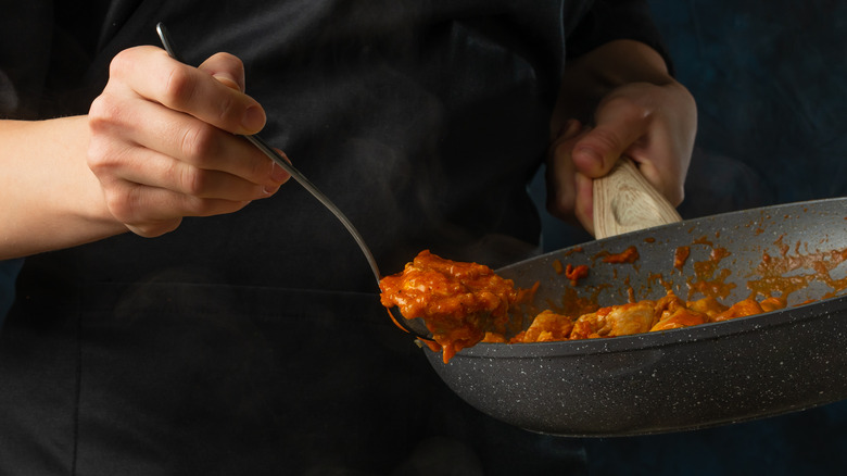 Chef spooning stew from pan