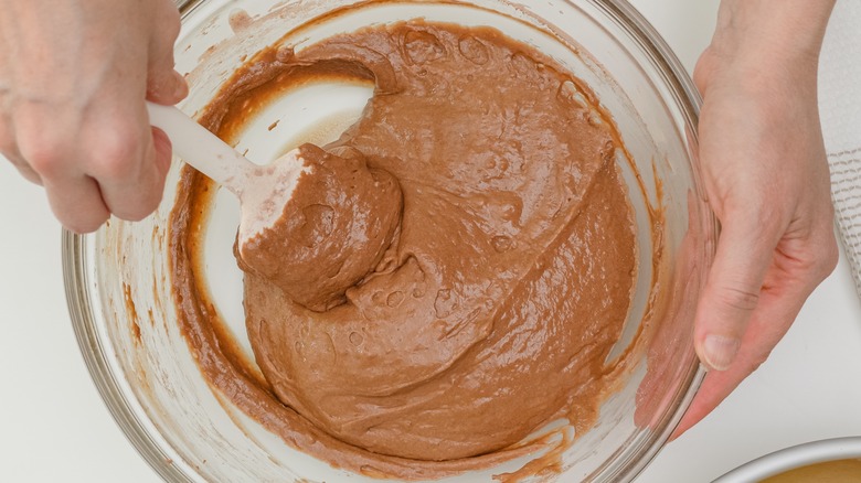 Person folding chocolate cake batter