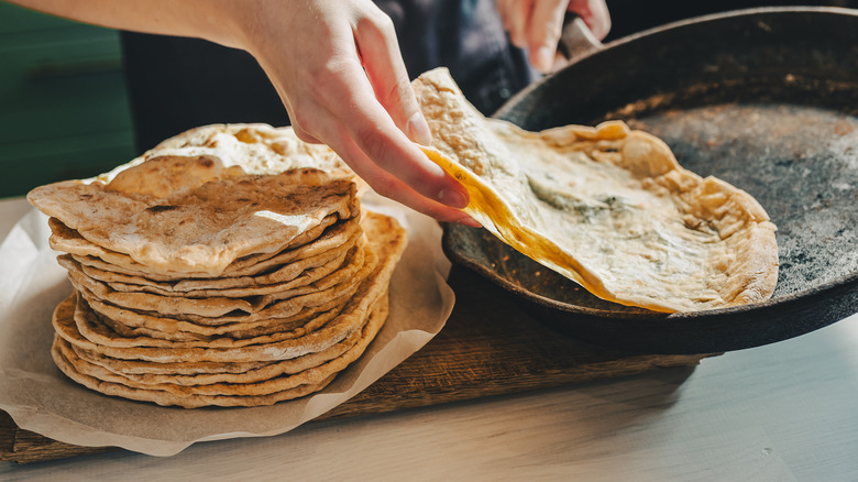 person removing tortilla from pan
