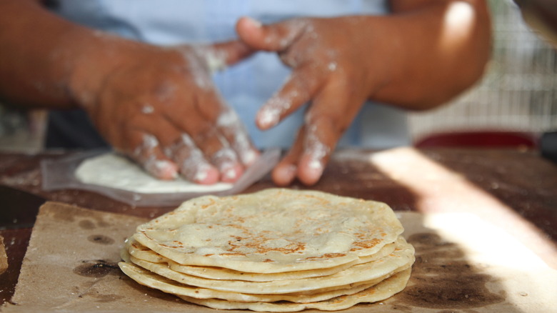 person making tortillas