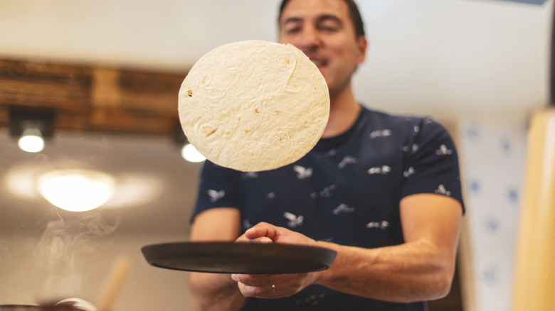 person flipping tortilla in pan