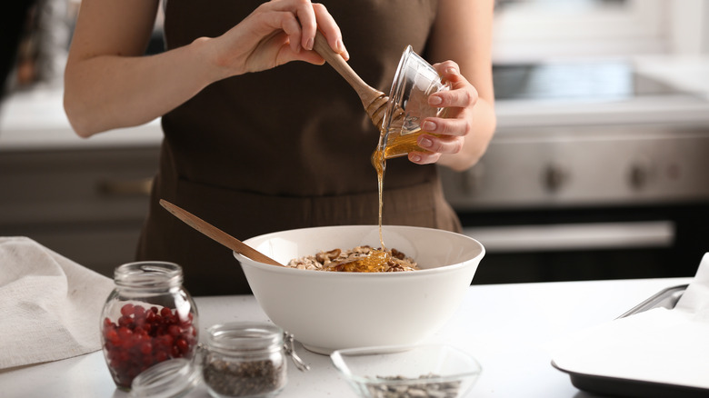 Person pouring honey into granola