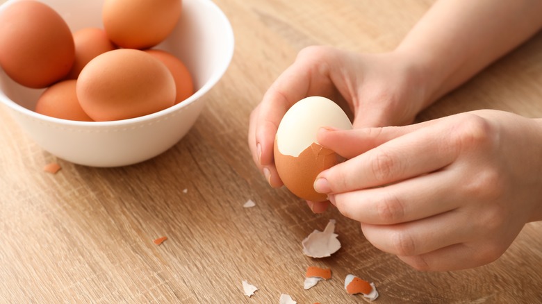 hand peeling eggs on table