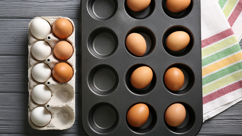 Brown eggs in a muffin tin by tea towels