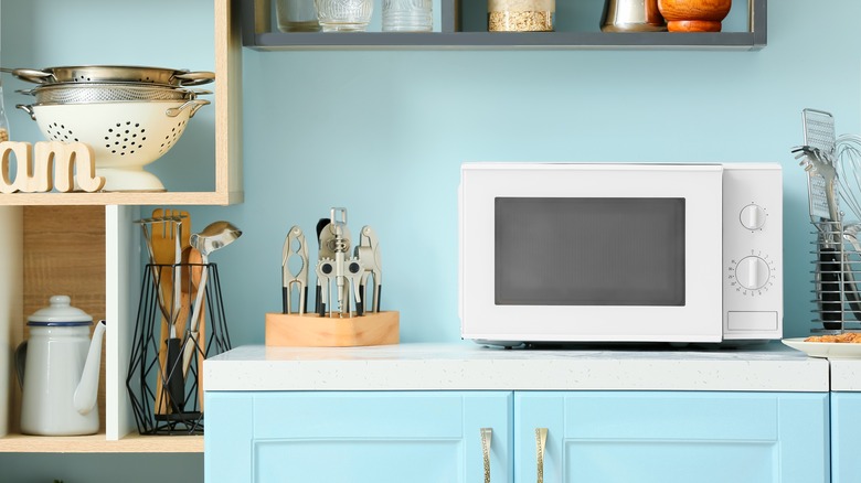 Microwave on white countertop in blue kitchen 