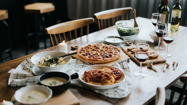 table setting with pasta, pizza, and wine