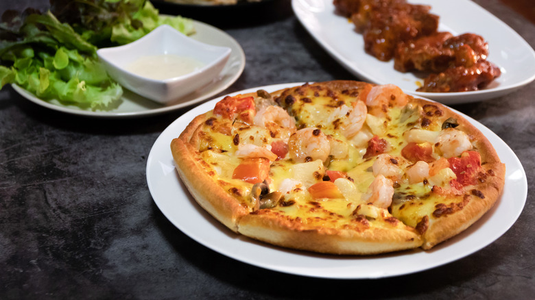 shrimp pizza with side dishes and chicken wings