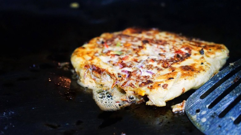 zanzibar pizza cooked on grill by metal spatula