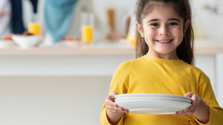 Small girl holding plates