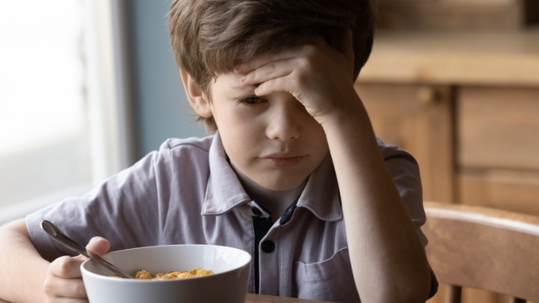 Unhappy boy with bowl of food