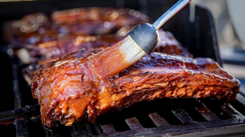 Ribs being basted with BBQ sauce