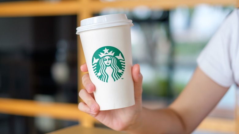 hand holding up Starbucks coffee cup