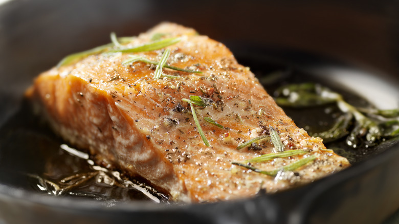 salmon in skillet with herbs