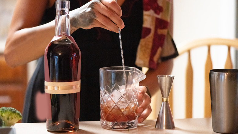 person stirring cocktail in mixing glass