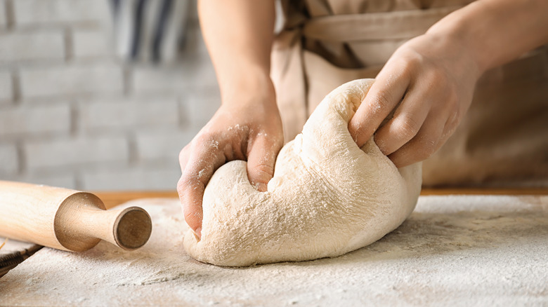 person kneading dough